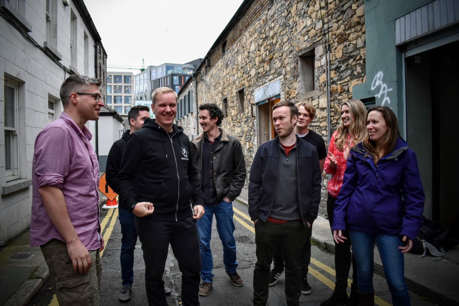 A number of Roadie employees talking to each other while standing in the middle of a small street